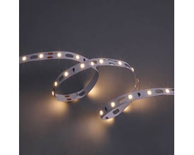 Tændt Ansell Lighting Z-Cell LED bånd, der udsender varmt hvidt lys (3000K), vist i bløde kurver på mørk baggrund.