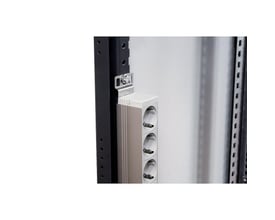 Lodret fastgørelsesbeslag fra Lauritz Knudsen monteret på et sort rackskab, med et hvidt og gråt powerpanel med tre stikkontakter.