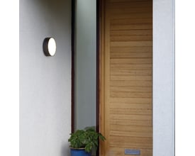 Astro 8022 Kea Round 250 sort LED væg- og loftlampe monteret ved en døråbning med en grøn plante foran.