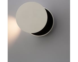 ANTIDARK Dot W120 LED sengelampe i hvid aluminium med en diameter på 120 mm, monteret på en grå væg og oplyst nedad.