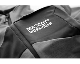 Close-up af et gråt Mascot Workwear mærke på et stykke tekstil, sandsynligvis et arbejdstøj.
