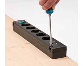 Brennenstuhl Bremounta sort stikdåse med USB-oplader fastgøres med skruetrækker; fem udtag ses.