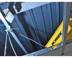 Ironside genopladelig LED-arbejdslampe sidder på en metalstruktur med den gule bagside og logoet synligt.