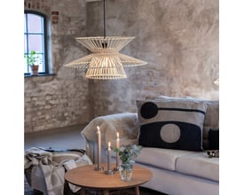 Markslöjd Duplici pendel i naturmateriale, monteret i en hyggelig stue med sofa og stearinlys.
