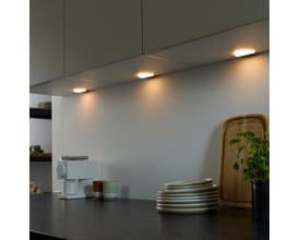 Loevschall Polaris Round LED lys med tænd/sluk sensor, monteret under køkkenskabe og oplyser køkkenbordet med varmt lys.