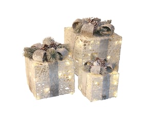 Sæt af tre Nordic Winter julepakker i forskellige størrelser, hvide med lys, sløjfer og kogler, isoleret på hvid baggrund.