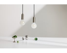 To Osram Ledvance LED globe 95 lyskilder hænger ned fra sorte ledninger, med dekorative elementer som små grønne blade og et lille metalkopper på et hvidt bord.