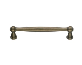 Beslagbodens bøjlegreb i antik messing med klassisk form og 128 mm centerafstand, set forfra.