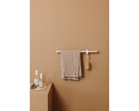 Metallbude Vana håndklædestangen i beige, monteret på en sandfarvet væg med et beige håndklæde hængende.