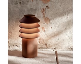 Louis Poulsen Bysted Garden pullert i lav model, corten finish, med fire lysringe der skaber nedadgående lys på rå murstensbaggrund.