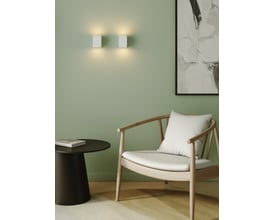 To Astro Lighting Mosto væglamper monteret på lysegrøn væg over et sofabord og en stol.