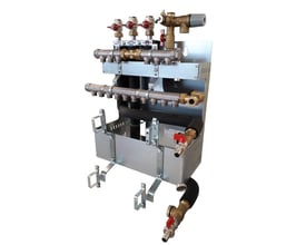 Detaljeret billede af Metro Therm Slimline fordelerunit, der viser tilslutningsdetaljer og samlinger med røde ventiler.