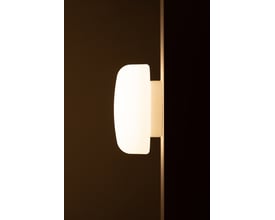 Sideprofil af Ifö Electric Solenne lampe monteret på væg, fremhæver den matte opalglas og hvide base i dæmpet belysning.