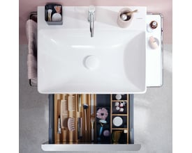 Hansgrohe IntraStoris skuffeinddeler i natur eg, vist i en åben skuffe med diverse toiletsager og kosmetik arrangeret.