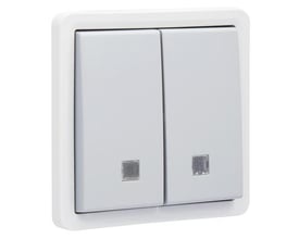 Niko fjedertryk med linse, dobbelt, IP55, grå. Hvid ramme med to grå kontakter og små lysende firkantede indikatorer forneden.