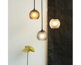 Tre Halo Design Nobb pendler i røgfarvet glas med 125 mm diameter, hænger ved siden af hinanden med lys tændt.