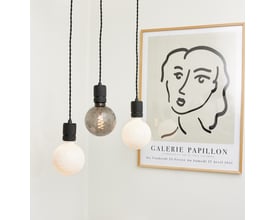 Tre Halo Design COLORS Geo lyskilder hænger ned fra sorte ledninger, med en kunstplakat i baggrunden.