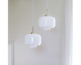 To Dyberg Larsen ARP pendler med opal glas og messing detaljer hænger side om side i en indretning.