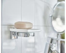 Smedbo ice vægmonteret sæbeskål i hvidt porcelæn med poleret krom detaljer, indeholdende en lys sæbe.