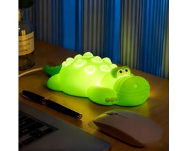 Mochi krokodille-natlampe lyser klart grønt på et skrivebord med computer og mus.