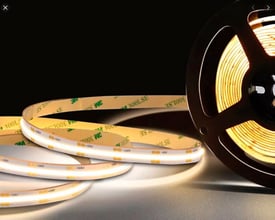 ALL-Light COB LED strip 5 meter 3000K RA90, 24V DC, 10W, vist sammen med en sort spole på en mørk baggrund.