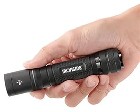 Sort Ironside genopladelig LED-lommelygte med riflet greb holdes i en hånd.