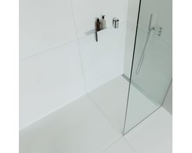 Unidrain HighLine panel på 1200 mm i håndpoleret stål, vist monteret i et moderne badeværelsesmiljø med glas brusevæg.