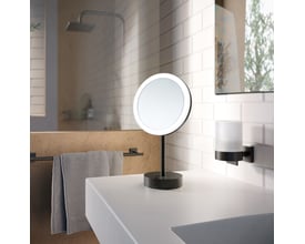 Smedbo Outline barber-/sminkespejl med LED-lys, 20 cm i diameter, mat sort finish på bordplade ved vask.