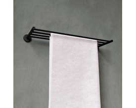 Cosmic håndklædeholder i mat sort med hvidt håndklæde hængende på væg med grønlig tekstur.