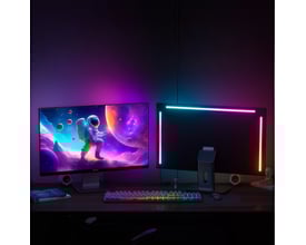 To computerskærme, den ene med astronaut-baggrund, den anden med RGBIC LED strip oplyst bagfra i lilla og blå nuancer.