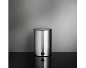 Unidrain Reframe pedalspand på 4 liter i håndpoleret stål, vist med låg lukket på sort blank overflade foran grå væg.