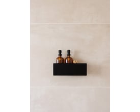 Metallbude Shea badehylde monteret på en flisevæg, indeholdende to ravfarvede sæbedispensere og en børste.