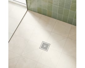 Hansgrohe afløbsskål monteret i et moderne badeværelsesgulv med lyse klinker og grønne vægfliser.