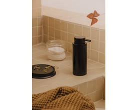 Cosmic Logic sæbedispenser i mat sort med 200 ml kapacitet, placeret på et badeværelsesbord med bomuldspads og smykker.