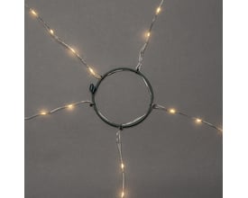 Konstsmide juletræskæde med 150 rav LED-lys arrangeret omkring en grøn metalring, vist på mørkegrå baggrund.