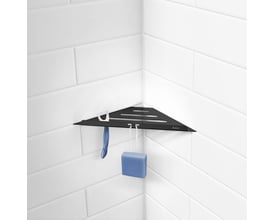 Smedbo Sideline sort hjørnehylde i rustfrit stål, vist monteret i et badeværelse med hvide fliser og badehåndklæde samt svamp hængende.