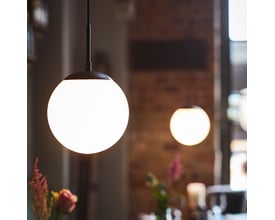 En enkelt Nielsen Light Cafe pendel med opal glas hænger i en hyggelig restaurant, belyst med blødt lys.