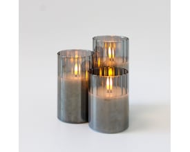 Tre LEDlife LED bloklys i røgfarvet glas med lysende flammeeffekt på en hvid baggrund.