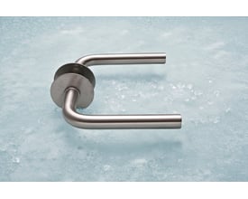 Assa Abloy L-formet dørgreb på 16 mm i børstet rustfrit stål med rund roset, set skråt fra oven.