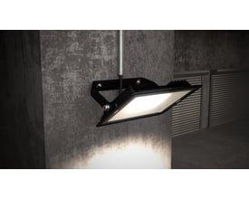 Ansell Lighting Eden LED projektør i sort, monteret på en betonvæg med lyset tændt, viser bred belysning udendørs.