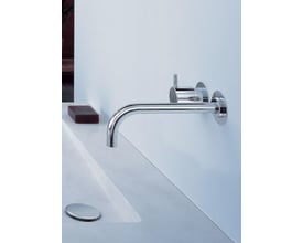 Vola 121 indbygningsarmatur til håndvask i krom med et-grebs betjening og fast, 225 mm lang tud monteret på en hvid væg ved siden af en sæbe.