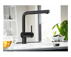 Blanco Linus-S køkkenarmatur i mat sort messing med L-tud og udtræksbruser, placeret ved en hvid vask.