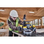 Håndværker med sikkerhedsudstyr bruger DeWalt 18V XR overfræser på træplade i et træbyggeri.
