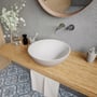 Ideavit Solidthin-39 håndvask i hvid mineral komposit, monteret på træbordplade med runde detaljer og blåmønstrede fliser.
