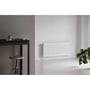 Stelrad Novello 8 radiator monteret i et stilfuldt rum med en grå væg og en stor grøn plante.