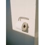 Knud Holscher toiletrulleholder fra d line monteret på flisevæg med en toiletrulle i børstet rustfrit stål.