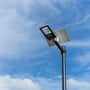 V-TAC solcelle-gadelampe monteret på en stolpe mod en blå himmel med skyer.