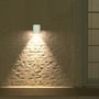V-TAC væglampen lyser ned ad en murstensvæg og viser den hvide udendørslampes lys på facaden.