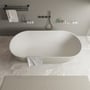 Ideavit Solidera fritstående badekar i grå solid surface materiale, 170x80 cm, placeret på marmoreret gulv med en grå håndklæde hængende på siden.