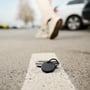 Sort Chipolo POP Bluetooth-tracker med nøglering ligger på en stenbordplade ved et nøglebundt.